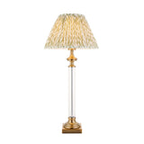 Endon Aldmont Leaf table lamp with a clear glass column, antique brass base and cap, and a pleated green leaf-print shade on a white background.