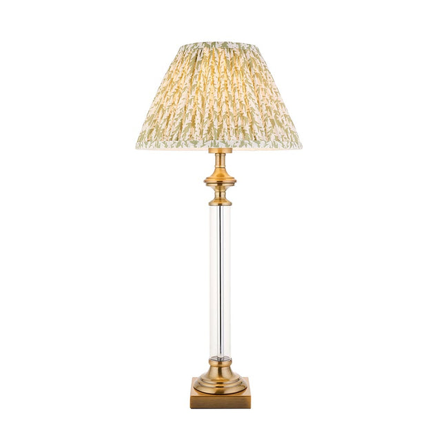 Endon Aldmont Leaf table lamp with a clear glass column, antique brass base and cap, and a pleated green leaf-print shade on a white background.