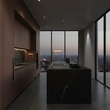 A modern kitchen with dark wood cabinets and a black marble island is illuminated by the Linea LED Alabaster Table Lamp – Brushed Brass. Minimalist lighting and floor-to-ceiling windows overlooking a cityscape create a sleek, sophisticated space.