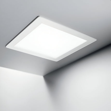 The Focus Square Recessed Downlight - 20W, 3000K in white is elegantly installed on the ceiling, providing energy-efficient lighting that spreads soft and even illumination across the smooth, white ceiling and walls for a minimalist and clean look.