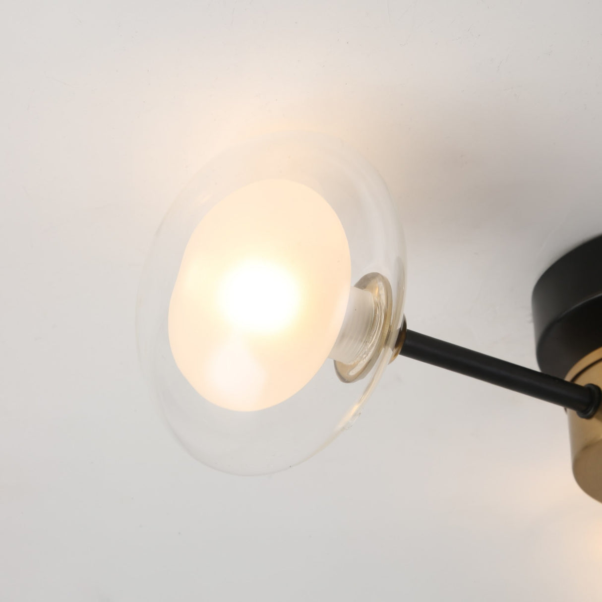 A close-up of the Galaxy 3 Light Wall/Semi-Flush Ceiling Light - Black & White shows its retro-inspired design with a round frosted glass shade and black and white accents, brightening a white ceiling.