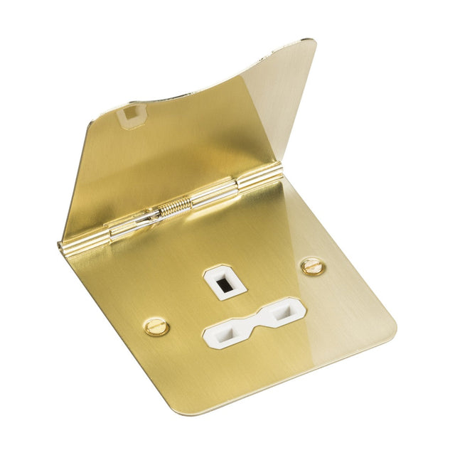 The 13A 1 Gang Unswitched Floor Socket in brushed brass, featuring a white insert and hinged cover, is open to display two plug openings and a switch socket. Designed to adhere to British safety standards, the socket cover boasts a shiny finish that beautifully reflects light.