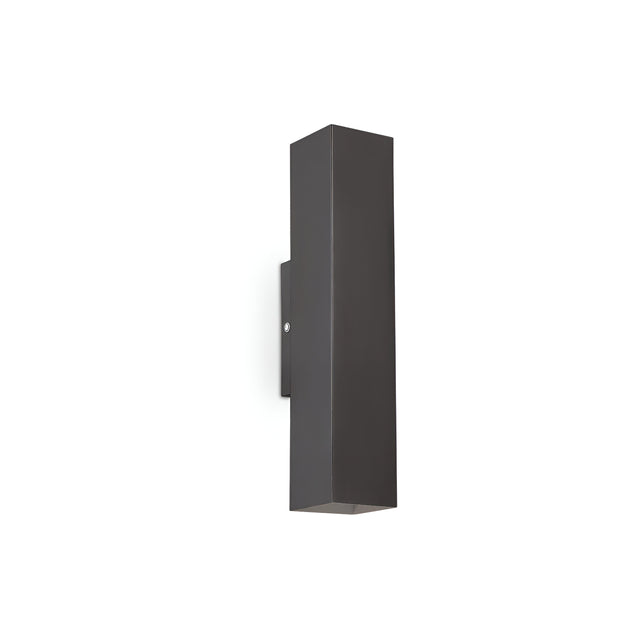 Against a plain white background, the Stellar 2 Light Wall Light - Black acts as a minimalist lighting element. This contemporary fixture features a sleek, vertical rectangular design with smooth surfaces and clean lines, elegantly casting light from both its top and bottom.