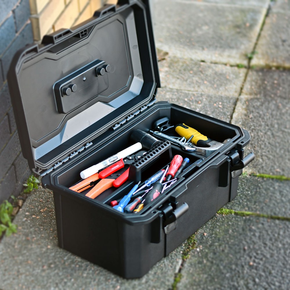 Open AVSL Mercury MTC-41 IP67 waterproof equipment case in matte black polypropylene, showing removable tray with hand tools inside, on paving outdoors.