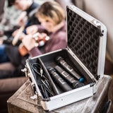 Chord MFC330 aluminium microphone flight case open on a crate, holding two wireless mics and coiled cables with a guitarist behind.