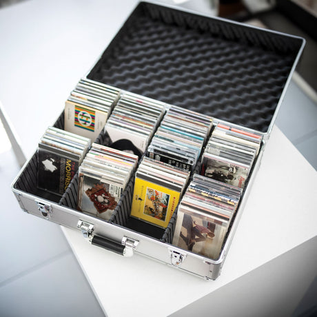 Citronic CDA:120 aluminium CD flight case open on a white surface, filled with CDs in padded separators and chrome catches on the front.