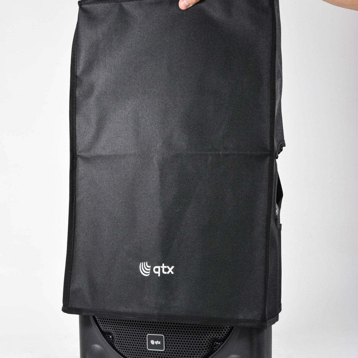 QTX QR12COVER water-resistant black slip cover fitted over a QR-series speaker cabinet with side handle access hole, held at the top against a plain background.