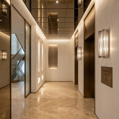 Modern, elegant elevator lobby with marble floors, warm lighting, and sculptural Mireya 6 Light Metal Chain Veil Wall Light - Nickel. Features a mirrored ceiling, two elevators, a sign reading Residences Level 1 A, and a staircase visible through a glass panel.