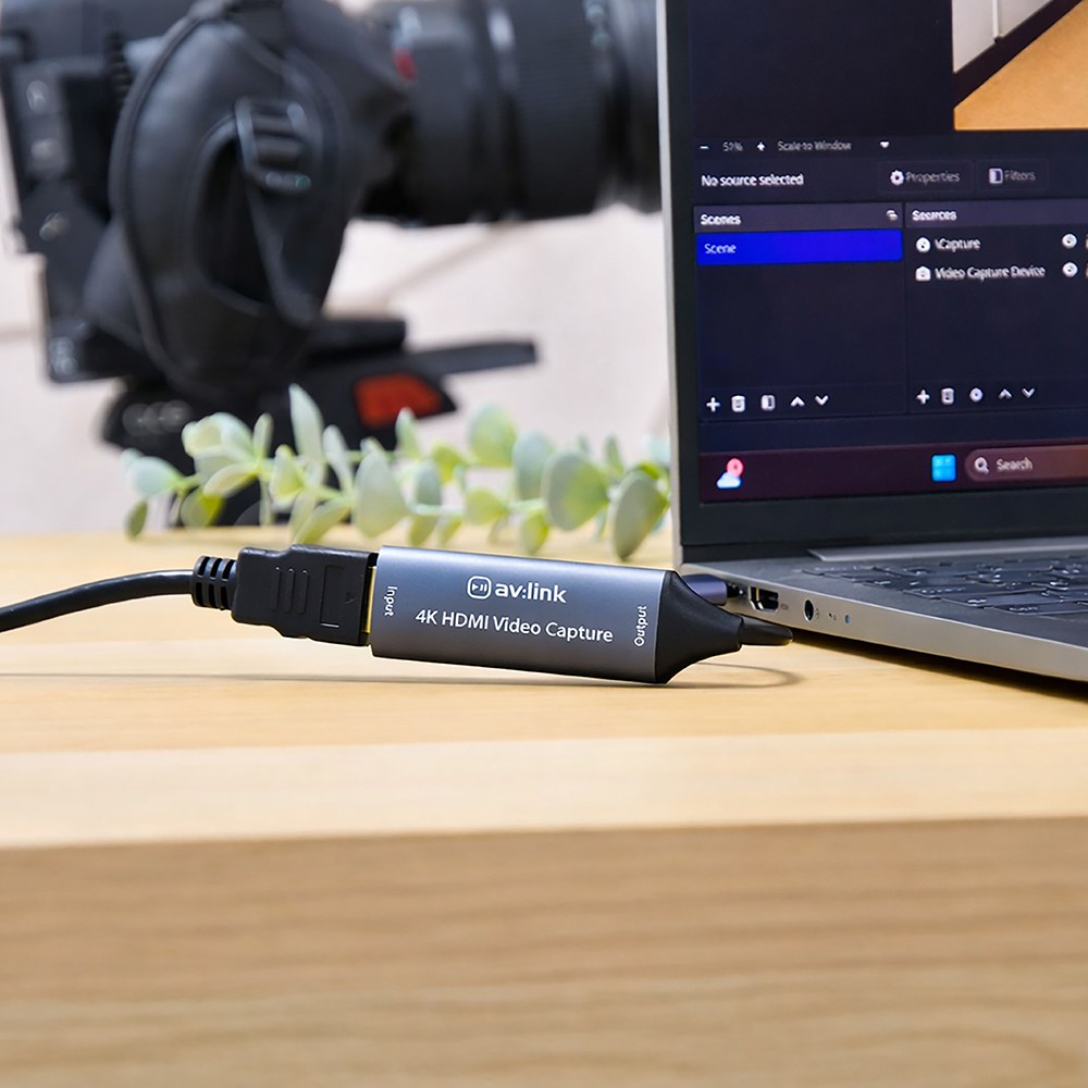 AV:Link HDVC4Kv2 4K HDMI Video Capture Card connected between an HDMI cable and a laptop running capture software on a wooden desk.