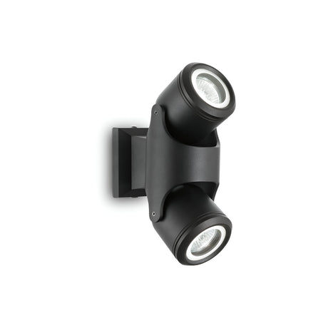 The Vista Outdoor Twin Spotlight - Black is a contemporary wall light fixture with an Outdoor Twin Spotlight design, featuring two cylindrical spotlights. Designed for versatile use indoors and outdoors, it mounts on a square base and includes adjustable diffusers to provide flexible lighting angles, enhancing modern outdoor aesthetics.