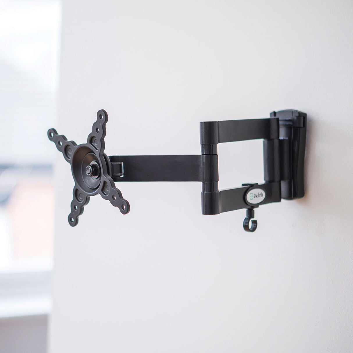 AV:Link HQT201 full motion double arm TV wall bracket in black steel, mounted on a white wall with arms extended and VESA plate visible.