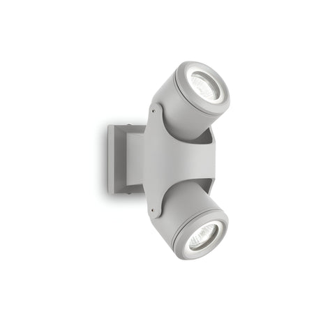 Introducing the Vista Outdoor Twin Spotlight in Grey: This contemporary wall-mounted fixture boasts a durable construction and two adjustable cylindrical heads that can be angled in opposite directions to ensure optimal lighting coverage. Specifically designed for outdoor use, it enhances security while offering excellent illumination.