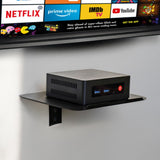 AV:Link ACS300 matte black wall-mounted accessory shelf by AVSL holding a small black media box below a wall-mounted TV displaying streaming apps.