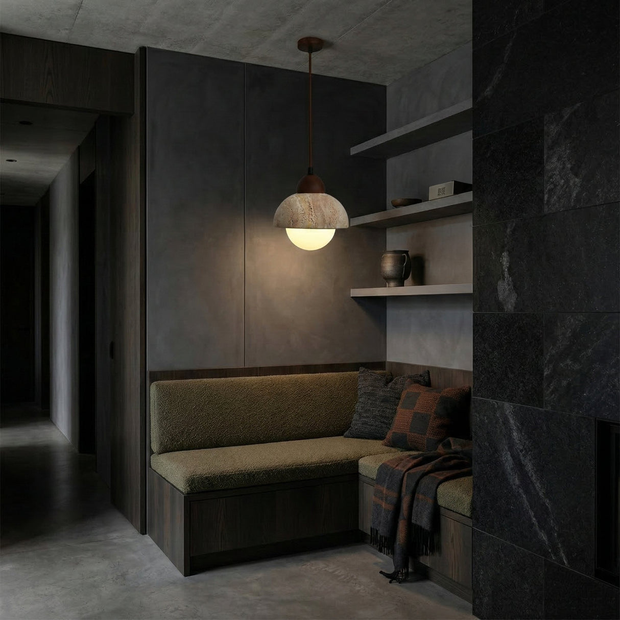 A cozy corner with olive green cushions, a checkered throw, and shelves of ceramics is softly lit by the Belaro 1 Light Dome Travertine Pendant in walnut brown & light beige, against dark minimalist walls and flooring.