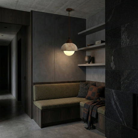 A cozy corner with olive green cushions, a checkered throw, and shelves of ceramics is softly lit by the Belaro 1 Light Dome Travertine Pendant in walnut brown & light beige, against dark minimalist walls and flooring.