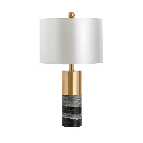The Valmora 1 Light Monolith Marble Table Lamp features a black and white marble-patterned base, brass accents, a white cylindrical shade, and is topped with a round gold finial for a modern touch.