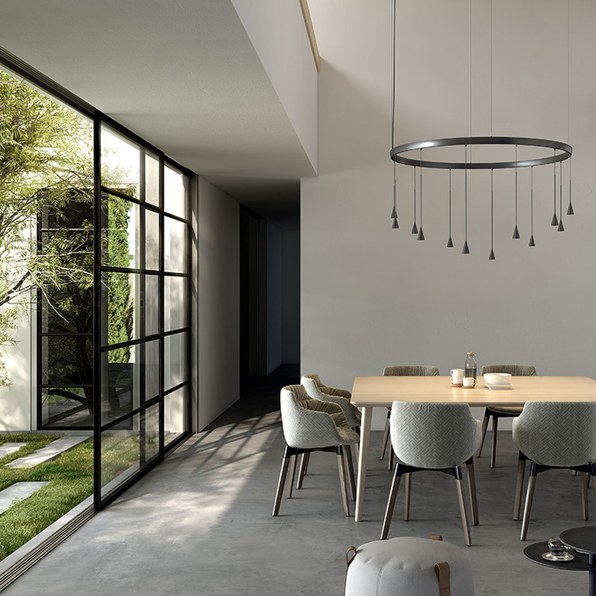 Skybell Circle Iron Ring LED Pendant Light in Ebony Black, a circular fixture with cone-shaped heads on slim stems, shown above a dining table in a modern living space.