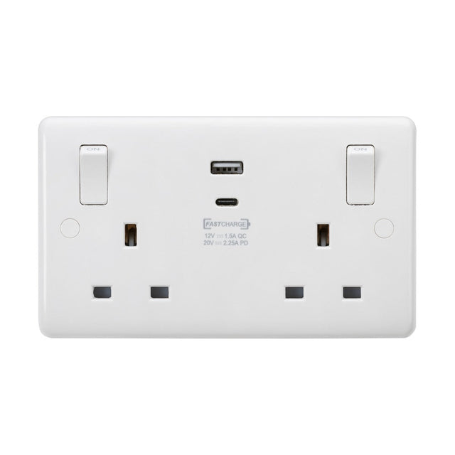 Introducing the 13A 2 Gang SP Switched Socket With Dual USB With Outboard Rockers (Rounded Edge), a stylish white dual electrical wall socket. It features a sleek design with a 7mm plate and a fast-charge USB-C port centrally located, alongside two standard plug outlets. Each outlet is equipped with an easy-to-reach switch positioned above, ensuring both style and functionality in one compact unit.