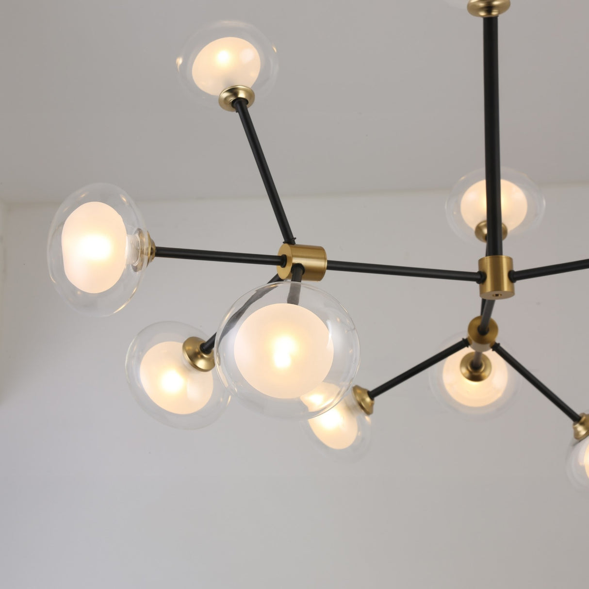 The Galaxy 12 Light Chandelier - Black & White is a modern fixture with black and white arms and multiple round glass globes, elegantly suspended from the ceiling.