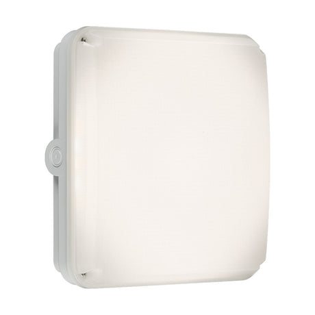The TENAX One Square Bulkhead Casing - White is a minimalist square LED ceiling light crafted from UV-stabilized polycarbonate, featuring rounded corners and IK10 impact resistance. It is mounted on a plain background and includes a subtle button detail on the side.