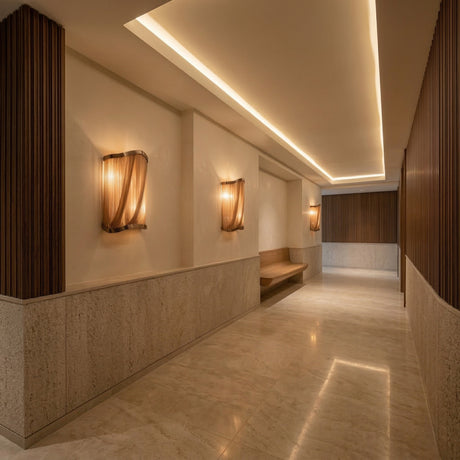 A modern hallway with marble floors, wood accents, and the Mireya 6 Light Metal Chain Veil Wall Light in Champagne exudes understated glamour. A sculptural wall feature and recessed strip lighting enhance the inviting ambiance.