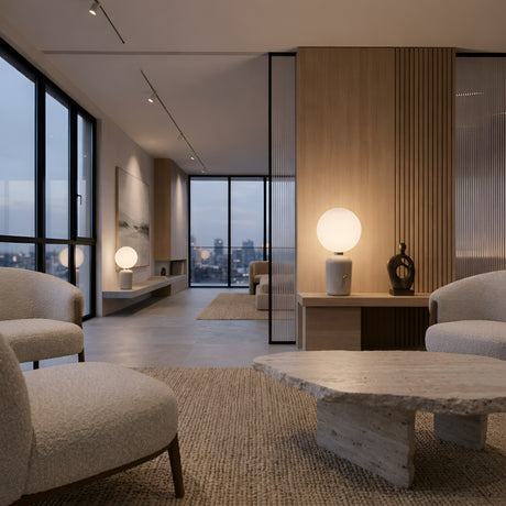 Modern living room with large windows, city view, beige armchairs, textured stone coffee table, neutral walls, minimalist decor, and soft lighting from the sleek white Pallo Table Lamp.