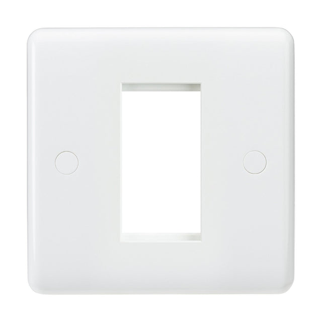 The 1 Gang Modular Faceplate is crafted from durable white thermoset resin and features a central rectangular opening, ideal for accommodating a light switch or outlet. Its smooth surface discreetly conceals two screw covers on either side, providing both functionality and style.