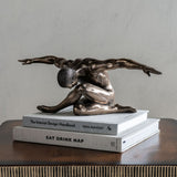 Libra Interiors Bronze Male Arms Outstretched Sculpture on stacked design books atop a dark wood console against a neutral wall.