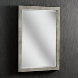 The Echo Rectangle Wall Mirror - Light Concrete, featuring its beige frame, is mounted on a textured dark wall. It reflects a soft, diffused light reminiscent of light concrete finishes, adding a subtle glow and enhancing the industrial design of the surrounding area.