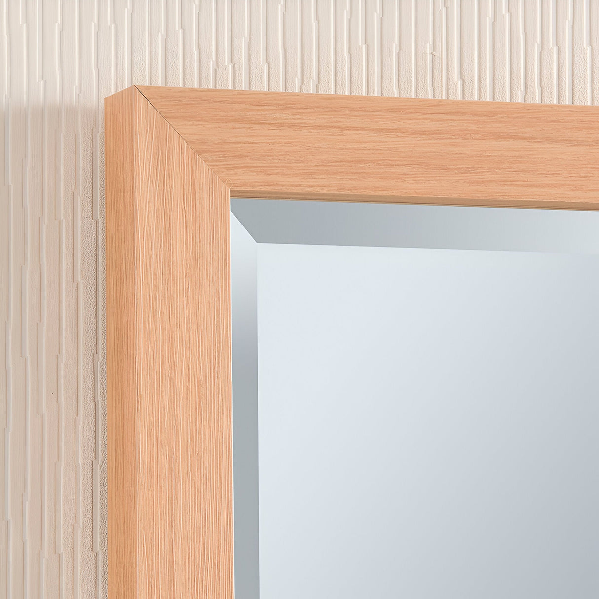 Close-up of the Eden Rectangle Wall Mirror - Oak on a textured beige wall. The light-colored oak frame exudes rustic elegance with its smooth finish, while the mirror softly reflects light, seamlessly blending with the wall's neutral tones.