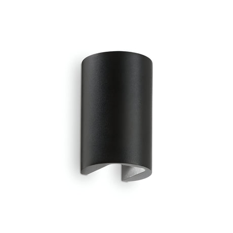 The Peak LED Outdoor Wall Light 6W 4000K - Black features a sleek, curved cylindrical design with an open bottom and is crafted from die-cast aluminium. Its minimalist style provides dual light emission, projecting light both upwards and downwards against a plain white background.