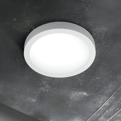 The Zephyrus Round LED Ceiling & Wall Light 13.5W 3000K in white, with its 17cm diameter, is elegantly mounted on a textured, dark gray ceiling. This energy-efficient fixture emits a gentle glow that enhances the ambiance of modern interiors.