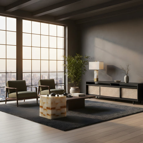 A modern living room with large windows, two green armchairs, a square marble coffee table, a black sideboard, a potted plant, and the Ravelle 1 Light Linear Column Alabaster Table Lamp. The city skyline is visible outside.
