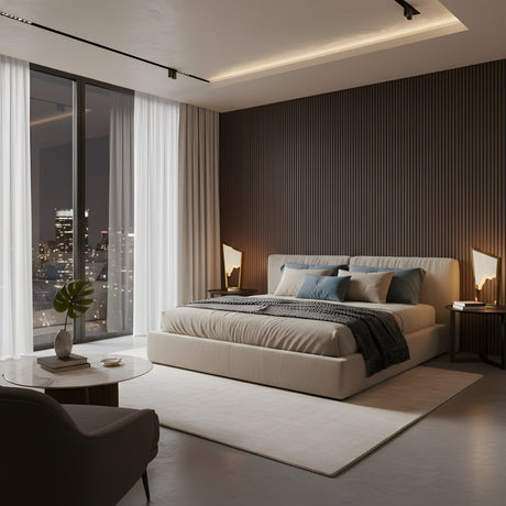 Modern bedroom with a large bed, soft lighting from an Atria LED Alabaster Table Lamp in Brushed Brass, dark accent wall, floor-to-ceiling windows framing a cityscape at night, round table with plant, and light rugs and curtains.