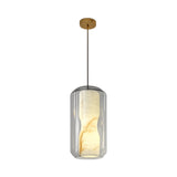 The Caldris 1 Light Faceted Alabaster Single Pendant Light - Soft White features a cylindrical glass shade with a marbled inner diffuser, suspended from a thin black cord and gold ceiling mount, for modern elegance.