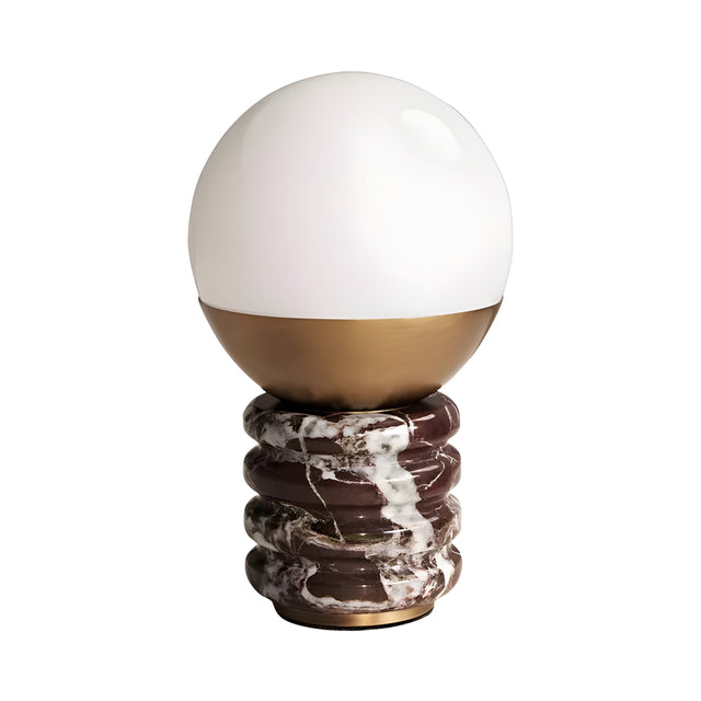 The Caldris 1 Light Sculpted Marble Table Lamp features a modern brass finish, a white glass globe, a gold half-sphere base, and a ribbed purple-red marble stand with white veining.