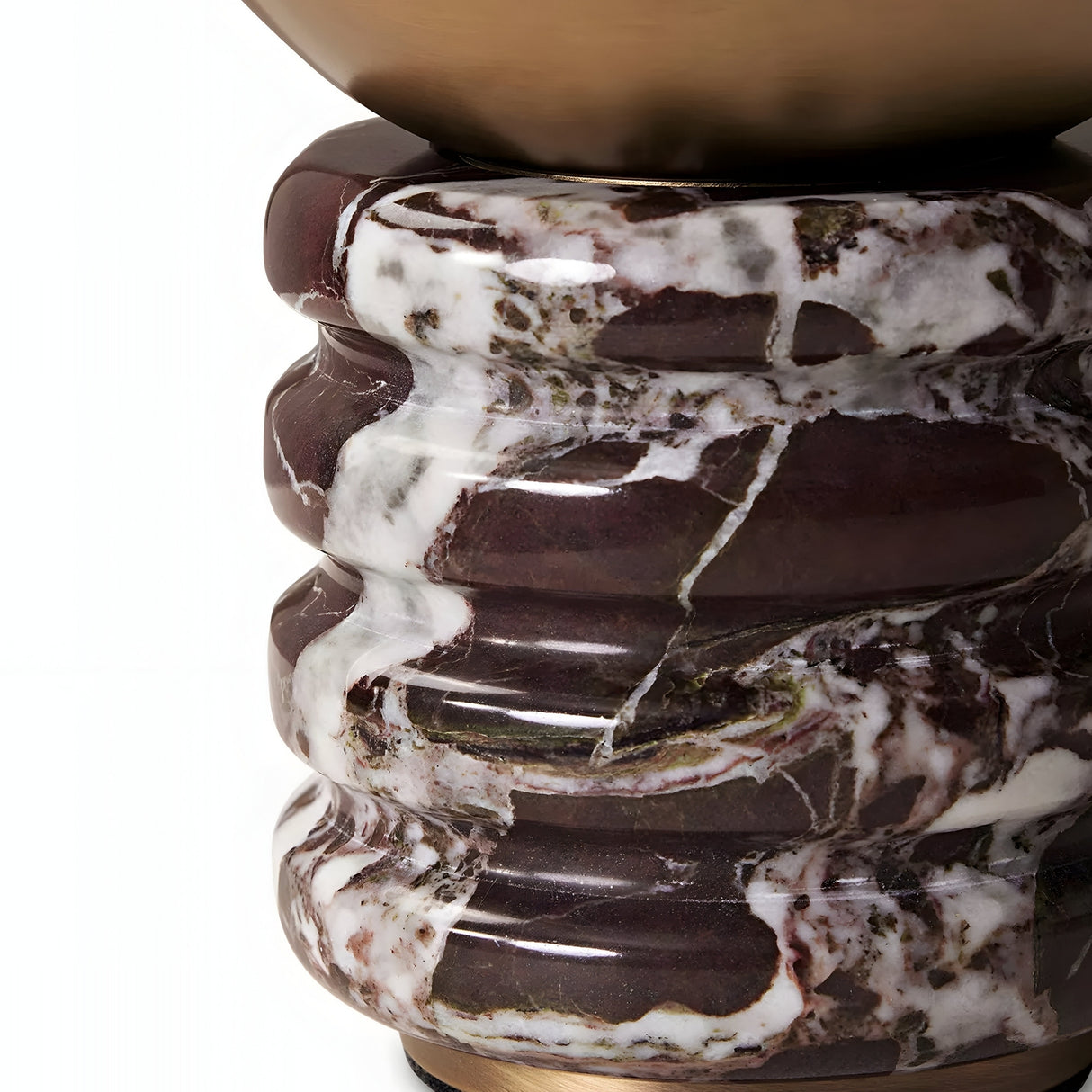 A close-up of the Caldris 1 Light Sculpted Marble Table Lamp in brass atop a purple red marble pedestal with rich veining and glossy texture.