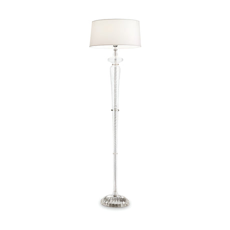 The Alloy Floor Lamp - White features a tall and elegant design with a clear, textured glass base and a round white lampshade. It provides ambient lighting while showcasing a classic and sophisticated appearance, standing gracefully on its decorative base that highlights modern elegance.