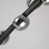 A close-up of the Cordaro 6 Light Leather Floor Lamp in black shows shiny metallic spheres on a sleek black rod, set against a plain white background.