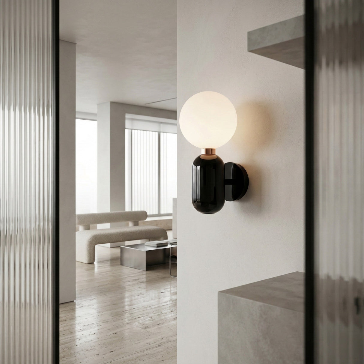 The Pallo Wall Light - Black with an opal glass diffuser is mounted on a white wall in a minimalist living room with light floors, neutral furniture, and large windows.