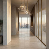 Niori Bubble 3 Light LED Glass Cluster Pendant in gold with clear glass spheres, hanging in a hallway with travertine floors and city skyline views.