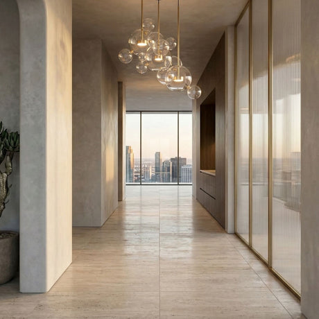 Niori Bubble 3 Light LED Glass Cluster Pendant in gold with clear glass spheres, hanging in a hallway with travertine floors and city skyline views.