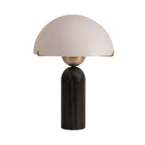 The Morvane 1 Light Sculpted Dome Table Lamp in black and white features a cylindrical black base, a gold spherical accent, and a sculpted white dome shade supported by thin gold brackets.