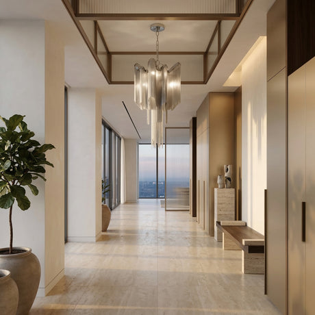 A modern, elegant hallway with large windows offering a city view, beige marble floors, the Valora 5 Light Metal Chain Veil Chandelier - Nickel, potted plants, and minimalist wooden furniture against light-colored walls.
