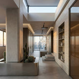 A modern, minimalist interior with floor-to-ceiling windows, neutral tones, a metal planter with cacti, built-in shelving, and the Bubble 5 LED Glass Cluster Pendant Light - Gold hanging from the ceiling.