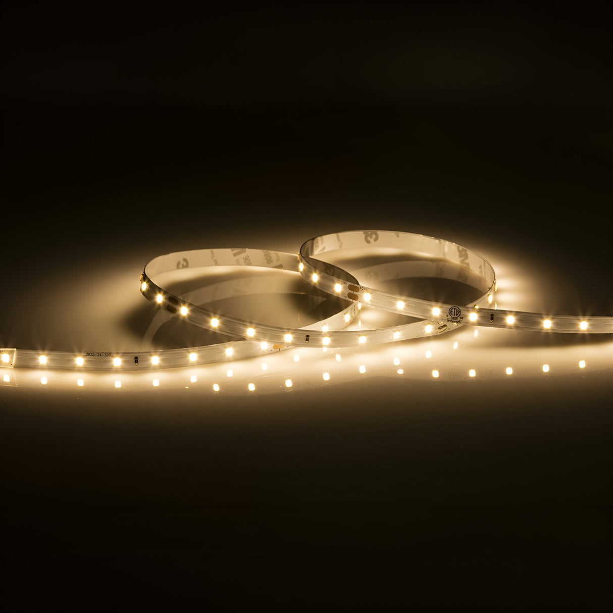 The 24V LED Strip Light 3000K - 3m emits a soft, warm white glow, elegantly coiled against a dark background to create an inviting and cozy atmosphere.