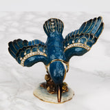Perched Kingfisher Metal Trinket Box with Hinged Lid in Blue, wings spread with crystal-studded trim and gold detailing, beak pointing down on an enamelled base, shown on a plain white background.
