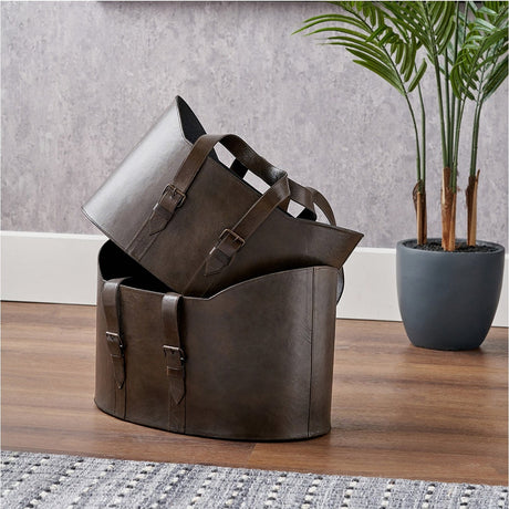 Alessio Set of 2 Peppercorn Leather Handled Storage Boxes, 34cm, with buckled straps, shown stacked on a wooden floor beside a potted plant.