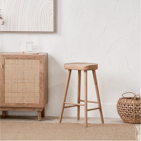 Laselle Ash Wood Bar Stool, 70cm, with a curved wooden seat and four tapered legs joined by a low footrest, shown in a neutral dining room setting.