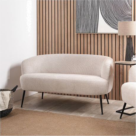 Aviana Natural Chenille & Black Metal Sofa, 130cm, curved back and rounded arms in natural chenille upholstery on slim black metal legs, shown in a living room against wood-slat panelling.